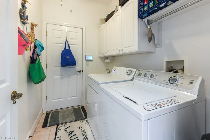 Washroom featuring tile patterned flooring, cabinets, and washing machine and dryer