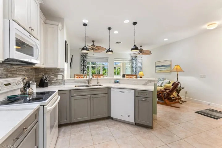 Kitchen with white appliances, tasteful backsplash, sink, ceiling fan, and light tile patterned flooring