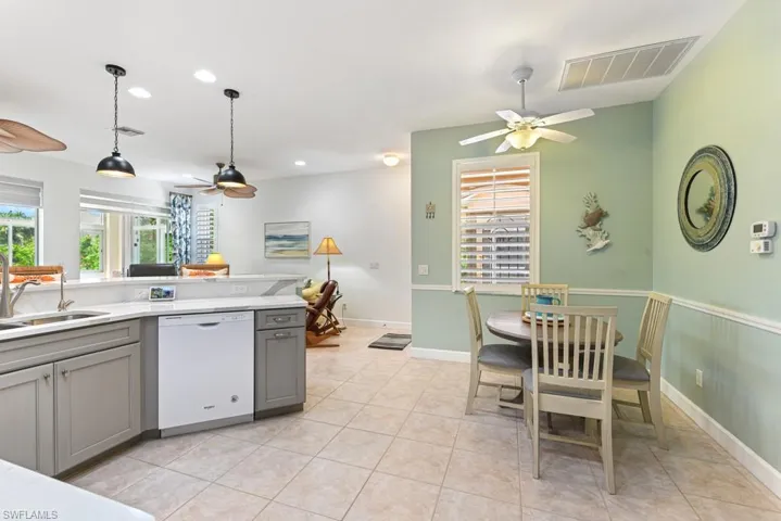 Kitchen featuring gray cabinets, light tile patterned floors, dishwasher, sink, and ceiling fan