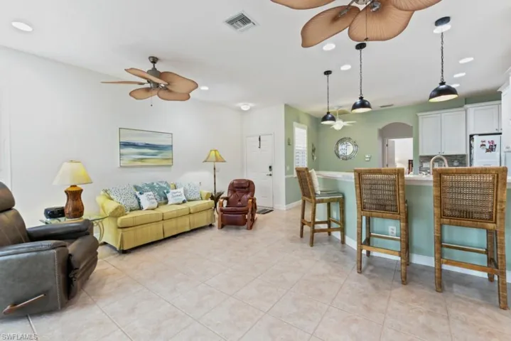 Living room with ceiling fan, light tile patterned floors, and sink