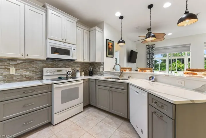 Kitchen featuring white appliances, sink, ceiling fan, decorative backsplash, and light tile patterned flooring