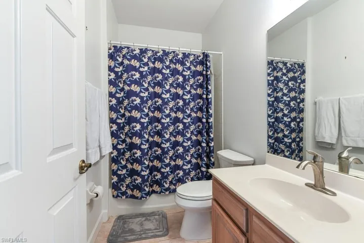 Full bathroom featuring shower / bathtub combination with curtain, vanity, toilet, and tile patterned floors