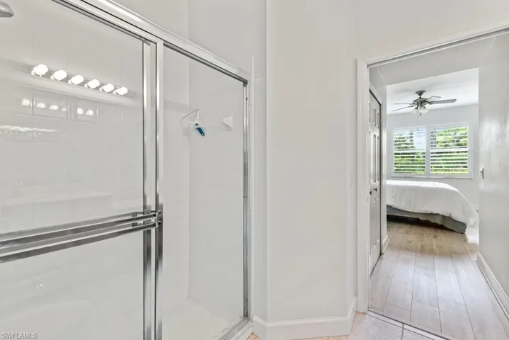 Bathroom featuring a shower with shower door, ceiling fan, and hardwood / wood-style floors