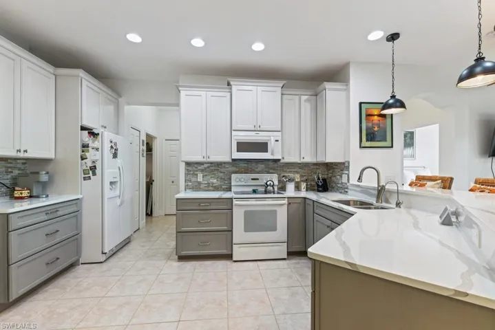 Kitchen with white appliances, gray cabinetry, and backsplash