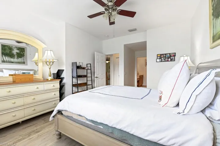 Bedroom with light wood-type flooring, ceiling fan, and ensuite bath