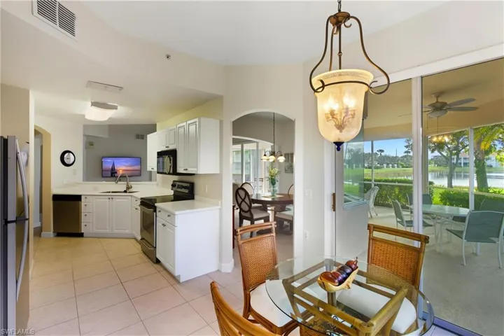 Kitchen with arched walkways, a chandelier, appliances with stainless steel finishes, white cabinets, and light tile patterned flooring