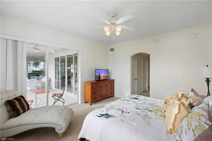 Carpeted bedroom featuring access to outside, arched walkways, and ceiling fan