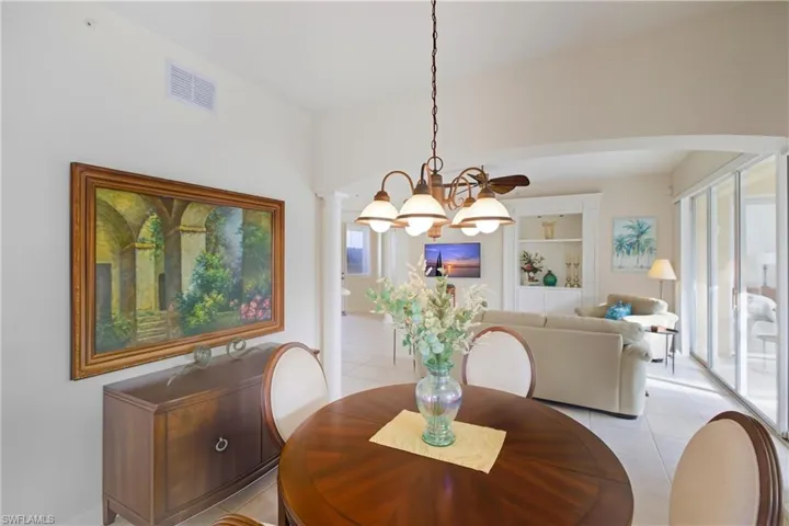 Dining space with tile patterned flooring, a chandelier, and decorative columns