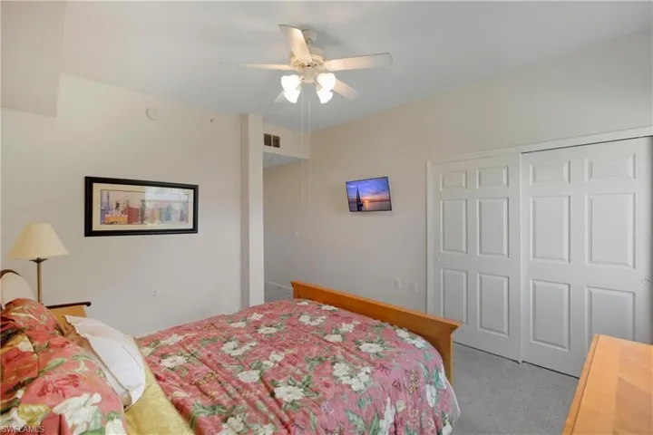 Carpeted bedroom with a ceiling fan and a closet