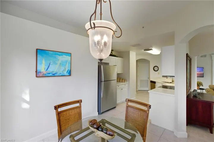 Dining space featuring arched walkways and light tile patterned floors