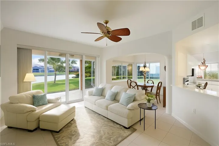 Living area featuring light tile patterned floors, a water view, a ceiling fan, and arched walkways