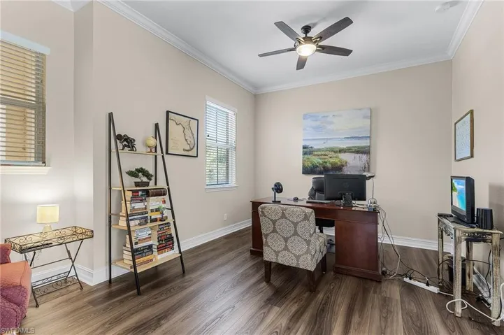 Home office featuring crown molding, ceiling fan, and dark wood-type flooring