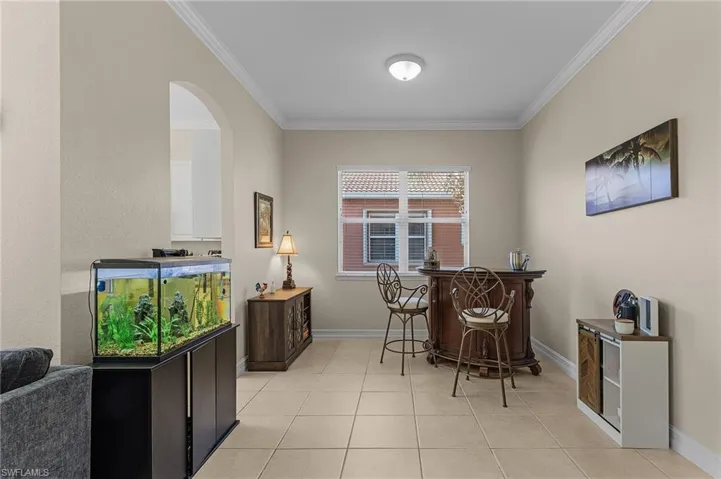 Tiled dining room featuring bar area and ornamental molding