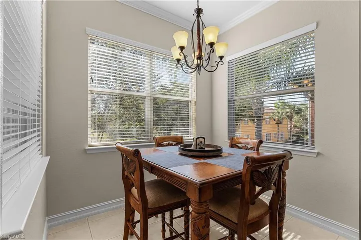Dining room with a notable chandelier, light tile patterned flooring, and ornamental molding