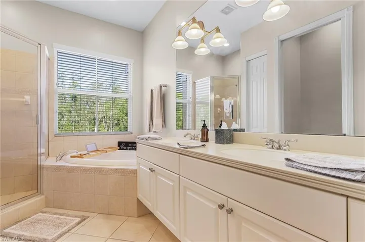 Bathroom with tile patterned floors, vanity, a chandelier, and shower with separate bathtub