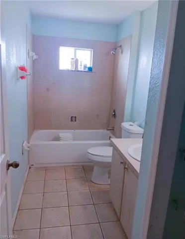 Full bathroom with tile patterned flooring, toilet, tiled shower / bath combo, and vanity