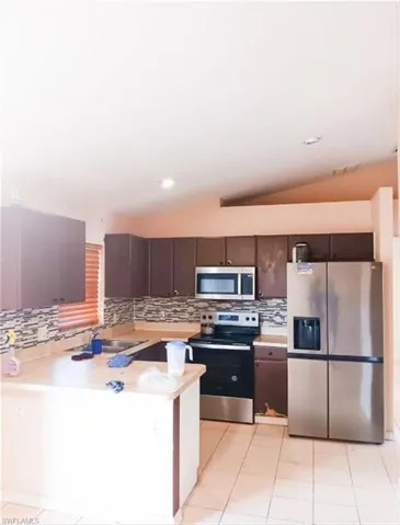 Kitchen featuring lofted ceiling, appliances with stainless steel finishes, and kitchen peninsula