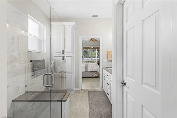 Ensuite bathroom with a marble finish shower, vanity, and a ceiling fan