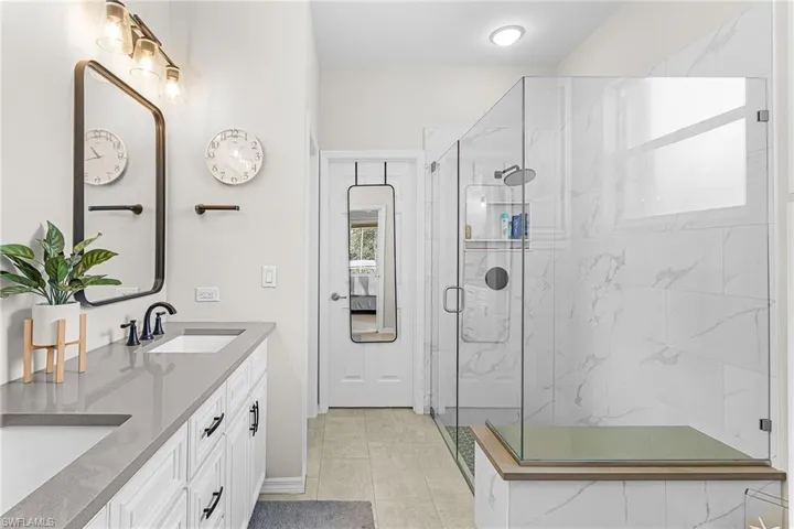 Bathroom with a marble finish shower and double vanity