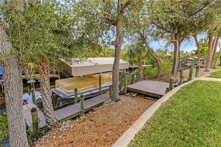 View of yard featuring a dock, boat lift, and a water view