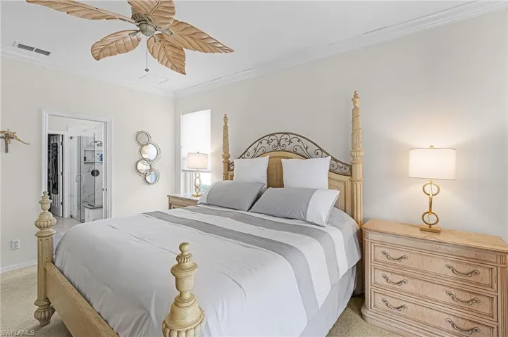Bedroom featuring light colored carpet, crown molding, a ceiling fan, and ensuite bath