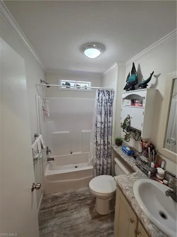 Full bath with vanity, dark wood-style floors, shower / bath combination with curtain, a textured ceiling, and crown molding