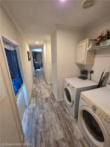 Laundry area with crown molding, dark wood-style floors, washing machine and clothes dryer, and cabinet space