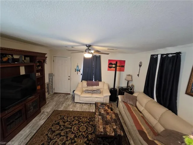 Living room with wood finished floors, a ceiling fan, and a textured ceiling