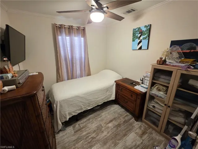 Bedroom with ornamental molding, wood finished floors, and a ceiling fan
