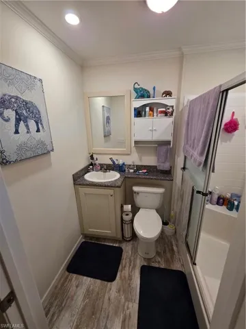 Bathroom featuring a stall shower, crown molding, dark wood finished floors, and vanity