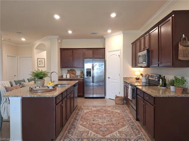 Kitchen featuring stone countertops, a center island with integrated sink, stainless steel appliances, and recessed lighting