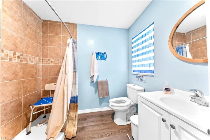 Full bathroom featuring vanity, toilet, shower / bath combination with curtain, and hardwood / wood-style floors