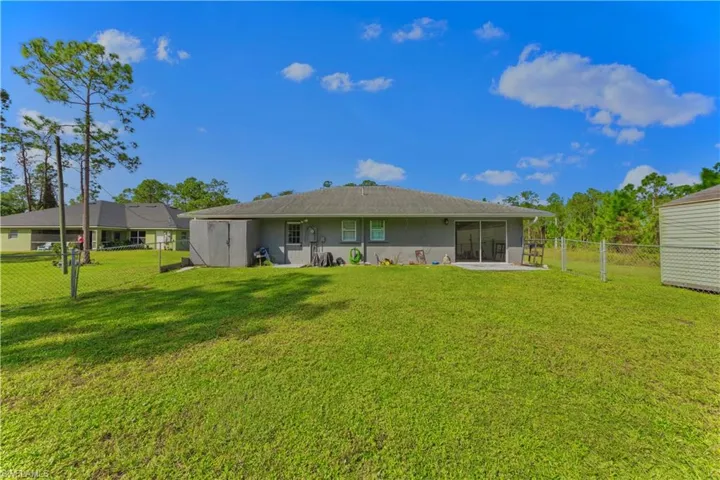 Back of house with a shed, a yard, and a sunroom