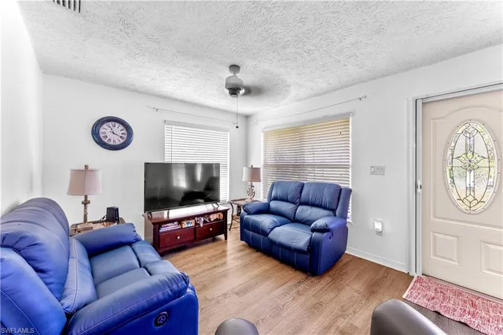 Living room with a textured ceiling, light hardwood / wood-style flooring, and plenty of natural light