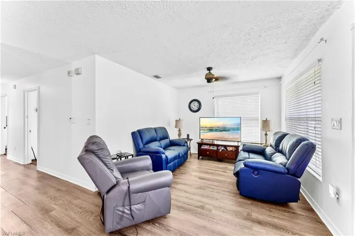 Living room featuring ceiling fan, a textured ceiling, and light wood-type flooring