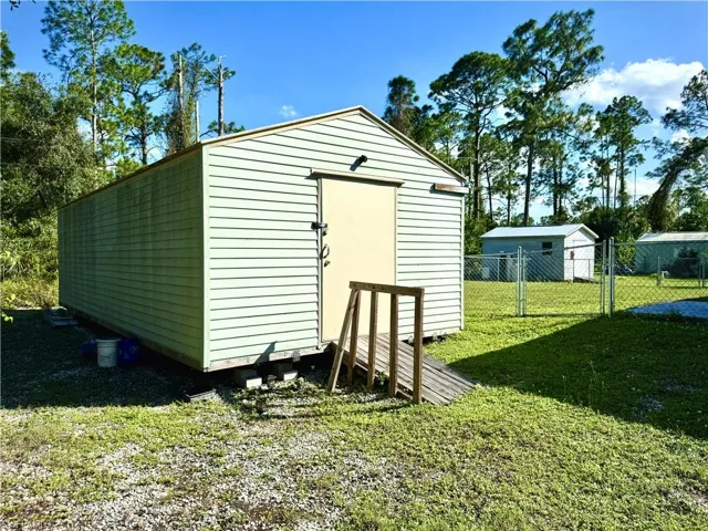 View of outdoor structure featuring a lawn