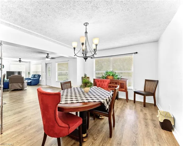 Dining space with a textured ceiling, ceiling fan with notable chandelier, and hardwood / wood-style floors
