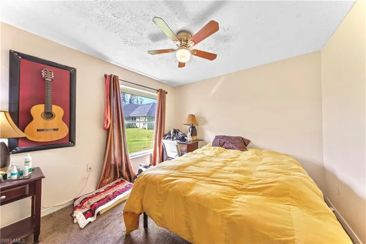 Bedroom featuring a textured ceiling, carpet flooring, and ceiling fan