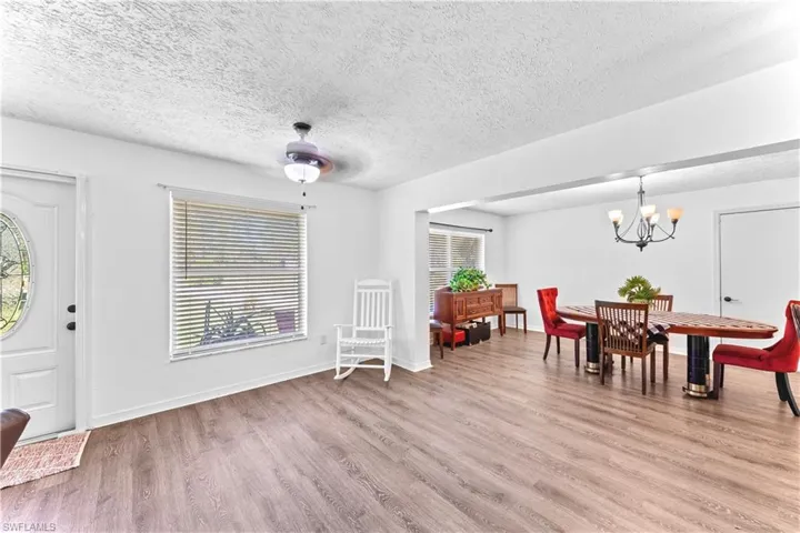 Foyer featuring plenty of natural light, a textured ceiling, ceiling fan with notable chandelier, and light wood-type flooring