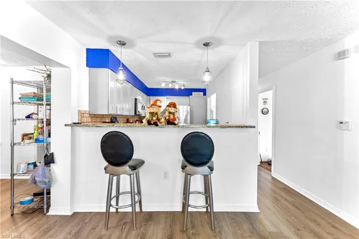 Kitchen with light stone countertops, light hardwood / wood-style flooring, and kitchen peninsula