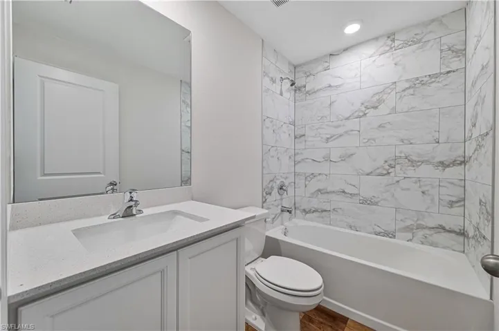 Full bathroom featuring vanity, hardwood / wood-style flooring, toilet, and tiled shower / bath combo