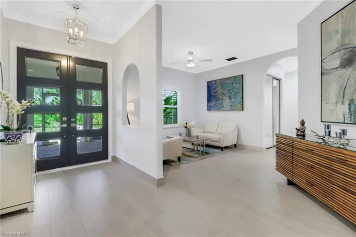 Foyer entrance featuring french doors, ornamental molding, a wealth of natural light, and ceiling fan with notable chandelier
