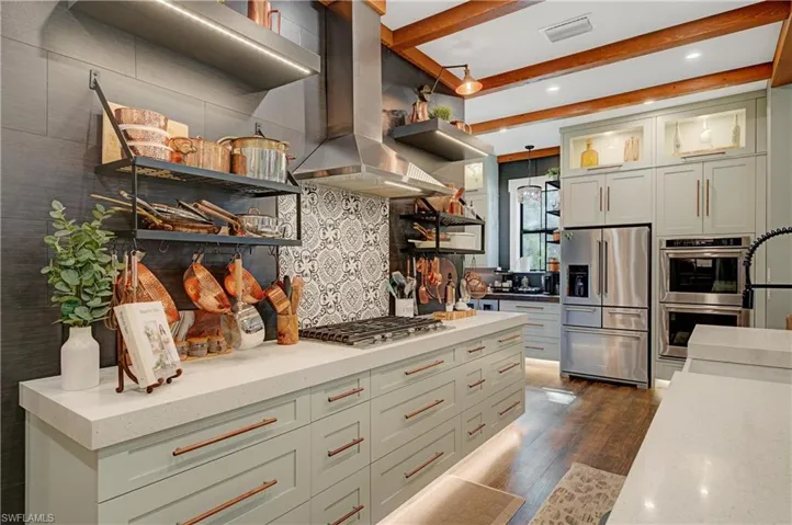Kitchen featuring island exhaust hood, tasteful backsplash, stainless steel appliances, beamed ceiling, and dark hardwood / wood-style floors