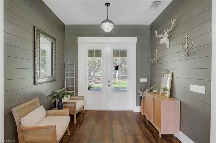 Doorway with dark hardwood / wood-style flooring and wooden walls