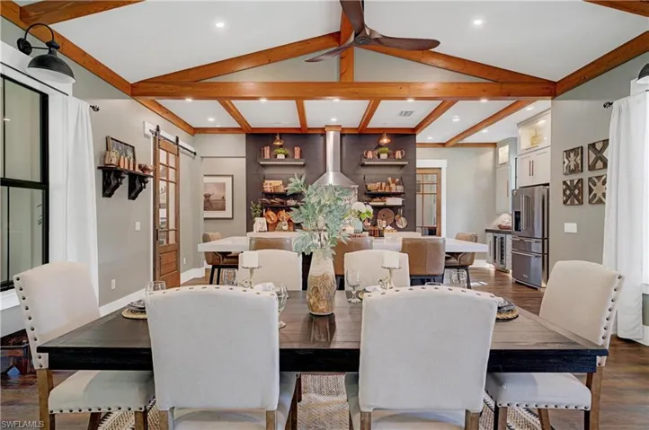 Dining room with vaulted ceiling with beams, a barn door, and dark hardwood / wood-style floors