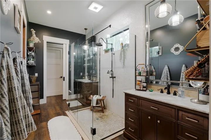 Bathroom with 2 vanities, wood-type flooring, and an enclosed shower