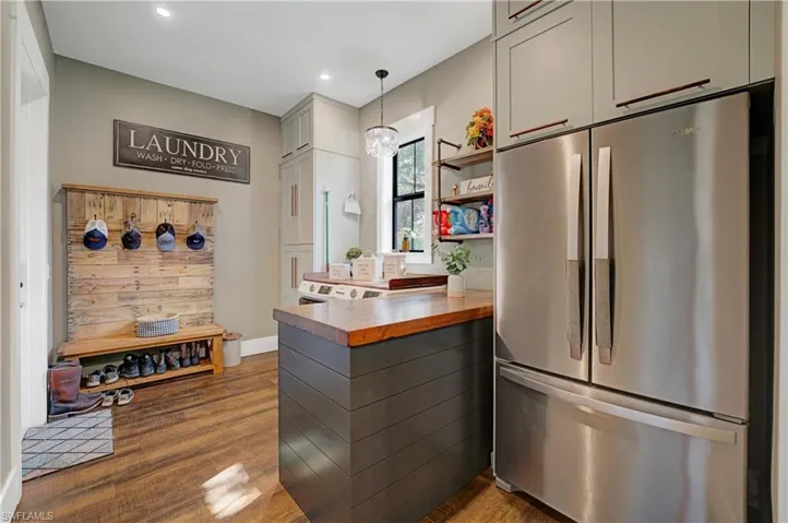 Laundry featuring hardwood / wood-style floors, butcher block counters, decorative light fixtures, stainless steel refrigerator, and gray cabinets
