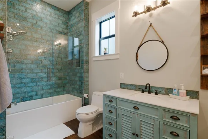 Full bathroom featuring vanity, hardwood / wood-style flooring, toilet, and enclosed tub / shower combo