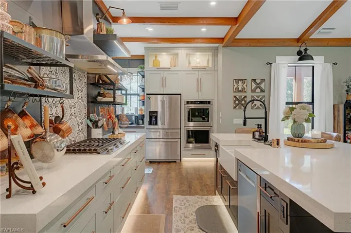 Kitchen featuring white cabinetry, sink, stainless steel appliances, hardwood / wood-style floors, and a spacious island