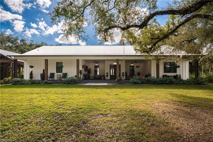 Rear view of property featuring covered porch, ceiling fan, and a lawn